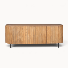 Aika dressoir Tansu in naturel hout met afgeronde hoeken, verticale lattenstructuur en slanke zwarte metalen poten.