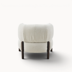 Achterkant van de Aika Tsuchi fauteuil met beige geweven bekleding en donkerhouten poten.