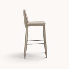Aika Floor barkruk in beige kunstleer met een slank design en metalen voetensteun, zijaanzicht.