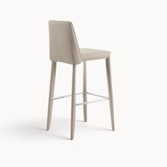 Aika Floor barkruk in beige kunstleer met een slank design en metalen voetensteun, gezien vanaf de achterkant.
