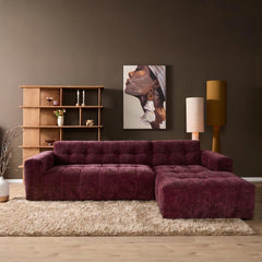 Aika MySofa Nagi loungebank in dieppaars met een getuft ontwerp op een beige hoogpolig tapijt in een modern interieur